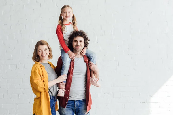 Pais felizes com adorável filhinha sorrindo para a câmera juntos — Fotografia de Stock