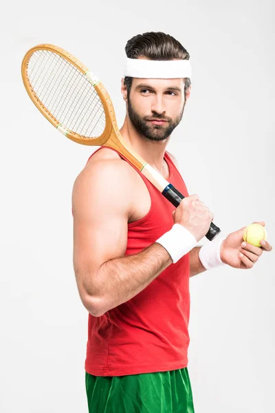 Tenista musculoso sosteniendo raqueta de madera retro y pelota, aislado en blanco - foto de stock