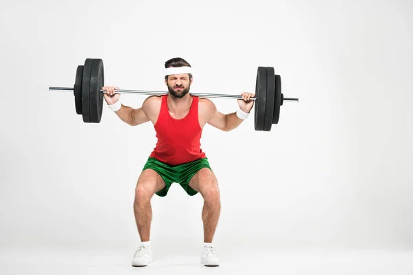 Deportista en ropa deportiva retro en cuclillas con barra, aislado en blanco - foto de stock