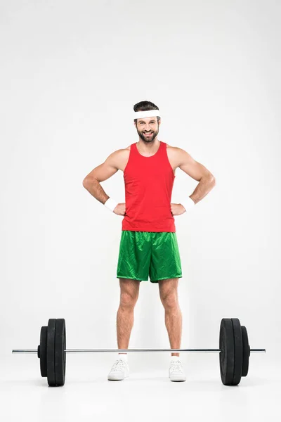 Sportif en tenue de sport rétro debout près de Barbell, isolé sur blanc — Photo de stock