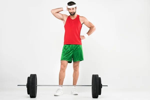 Thoughtful sportsman standing near barbell, isolated on white — Stock Photo