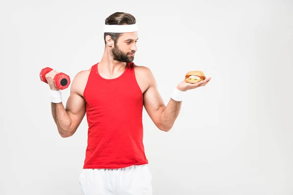 Sportsman choosing junk food or sporty healthy lifestyle, isolated on white — Stock Photo