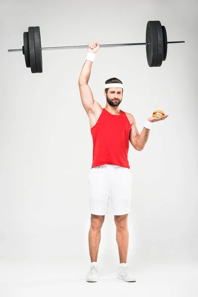 Deportista elegir hamburguesa o entrenamiento con barra, aislado en blanco - foto de stock