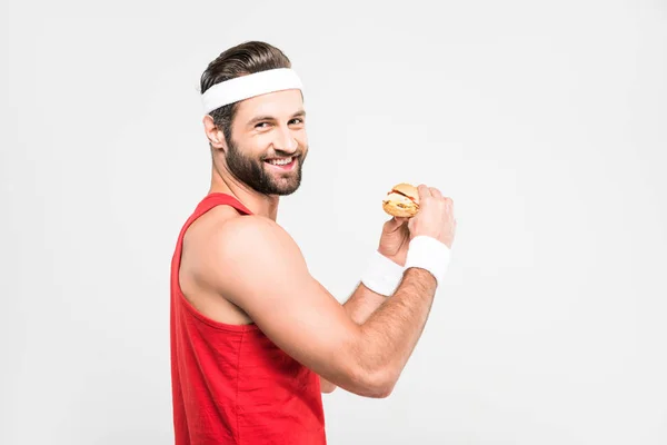 Sportler isst leckeren Hamburger, isoliert auf weiß — Stockfoto