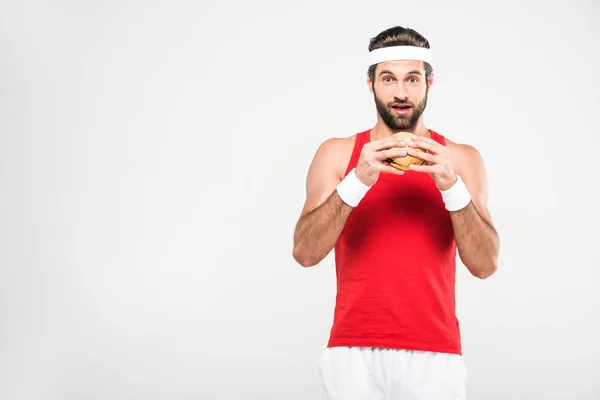 Excited sportsman eating hamburger, isolated on white — Stock Photo