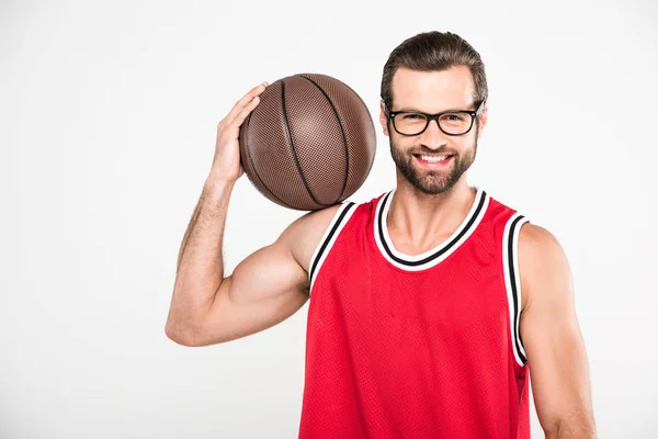 Cheerful basketball player in red sportswear holding ball, isolated on white — Stock Photo