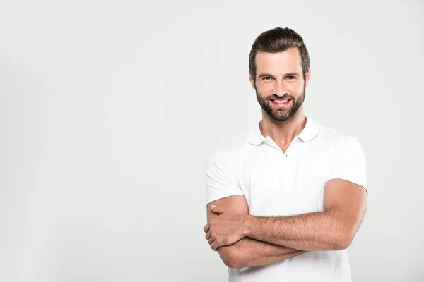 Handsome smiling man posing in white with crossed arms, isolated on grey — Stock Photo