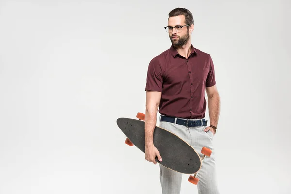 Eleganter gutaussehender Mann posiert mit Skateboard, isoliert auf grau — Stockfoto