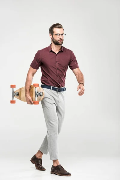 Stylish elegant skater walking with longboard, isolated on grey — Stock Photo