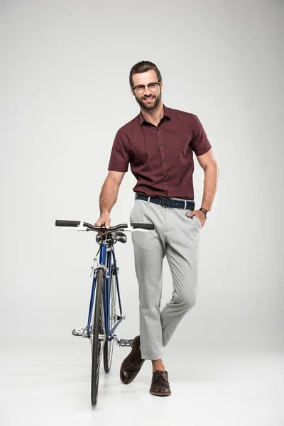 Uomo sorridente in posa con bicicletta, isolato su grigio — Foto stock