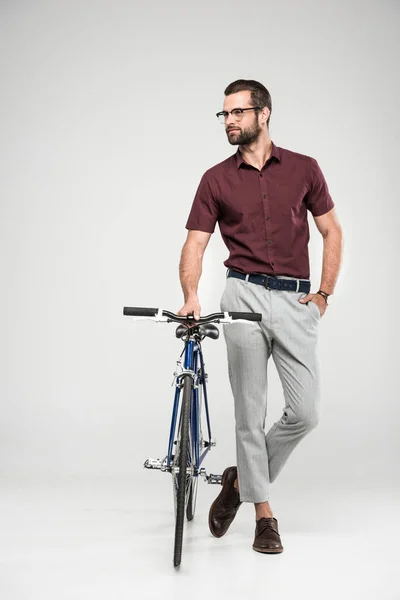 Bell'uomo in posa con bici, isolato sul grigio — Foto stock