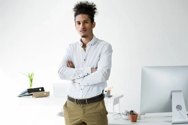 Portrait of young african american businessman standing with crossed arms and looking at camera — Stock Photo