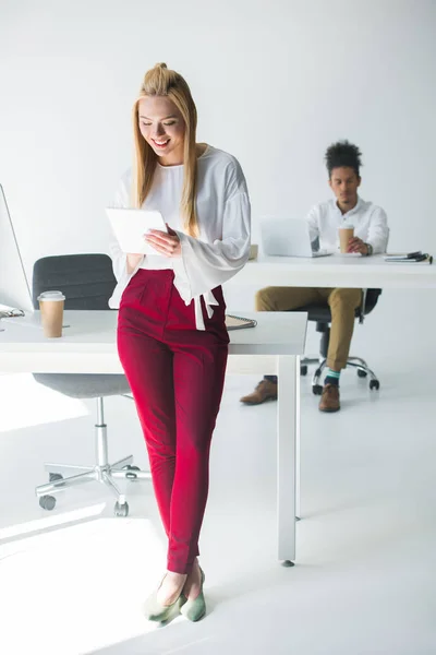 Hermosa joven mujer de negocios sonriente utilizando tableta digital en la oficina - foto de stock