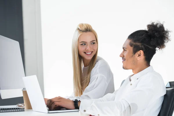 Jeunes collègues multiethniques qui se sourient tout en travaillant ensemble au bureau — Photo de stock