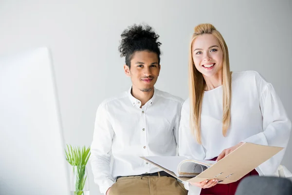 Fröhliche junge Geschäftsleute lächeln im Büro in die Kamera — Stockfoto