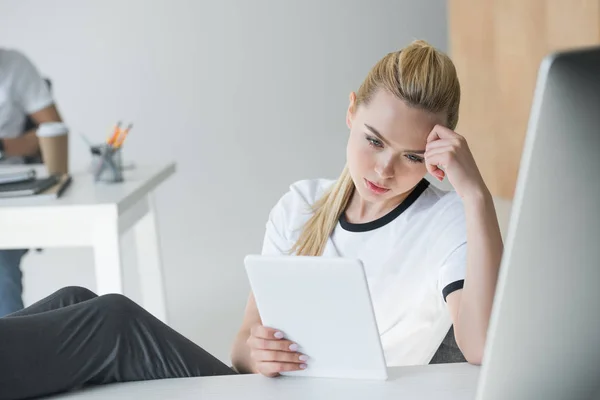 Junge blonde Frau nutzt digitales Tablet am Arbeitsplatz — Stockfoto