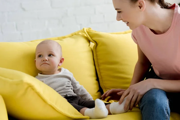 Madre sorridente con il bambino seduto sul divano — Foto stock