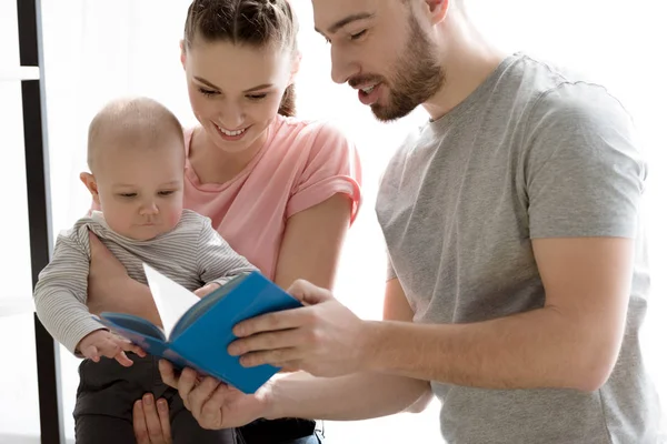 Happy family with baby boy dearing book together — Stock Photo