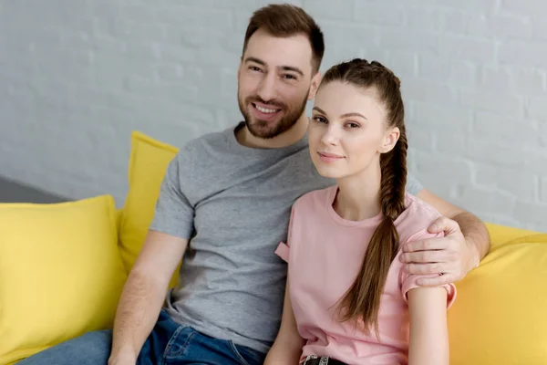 Felice coppia che si abbraccia e si siede sul divano — Foto stock