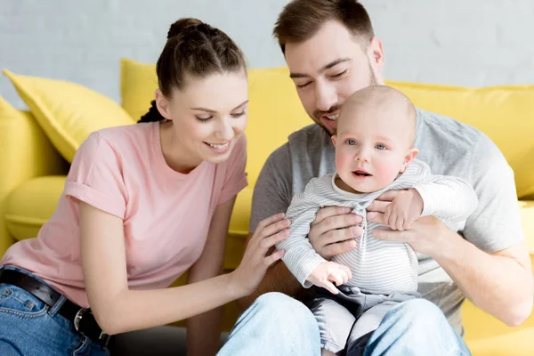 Parents souriants avec fils assis sur un canapé jaune — Photo de stock