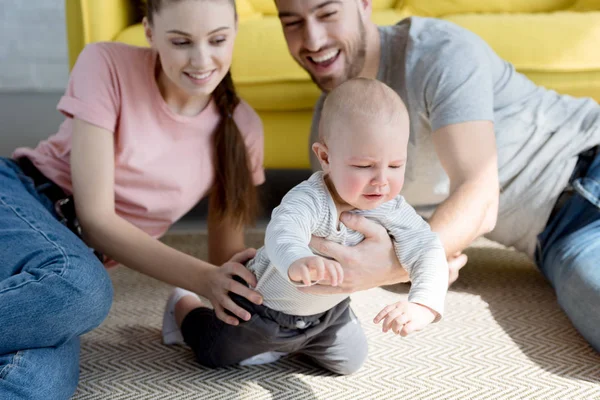 Happy parents playing with baby boy sitting on floor — Stock Photo