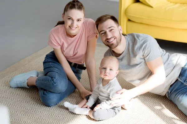 Happy family with baby boy sitting on floor — Stock Photo