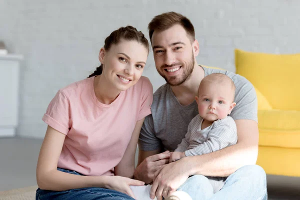 Famiglia sorridente con il piccolo figlio seduto a casa — Foto stock