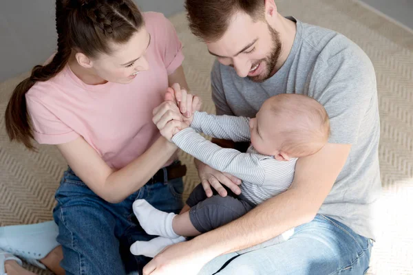 Happy parents playing with baby boy and sitting on floor — Stock Photo