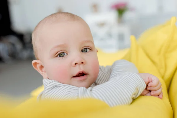 Adorable little baby boy on yellow sofa looking at camera — Stock Photo