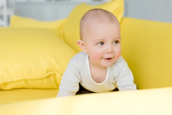 Adorable little baby boy on yellow sofa — Stock Photo