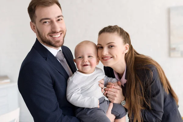 Smiling business parents holding baby at home — Stock Photo