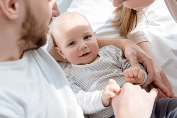 Young happy parents with little baby on bed — Stock Photo