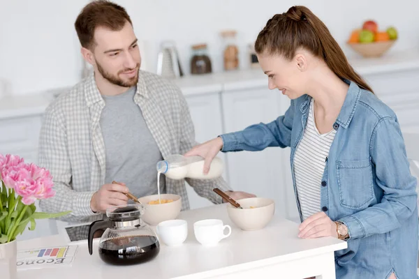 Jovem casal tomando café da manhã com flocos de milho e café — Fotografia de Stock