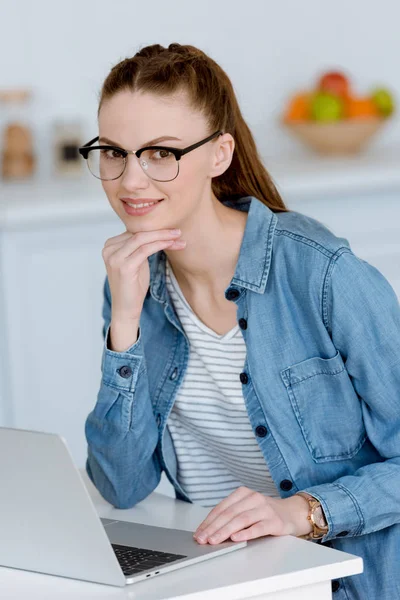 Jovem freelancer do sexo feminino trabalhando com laptop na cozinha — Fotografia de Stock