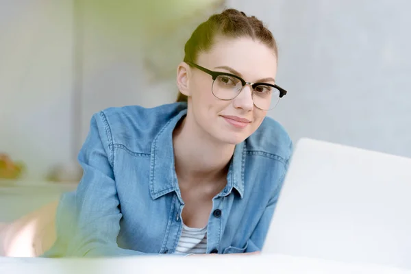 Atractiva mujer joven en gafas de vista utilizando el ordenador portátil - foto de stock
