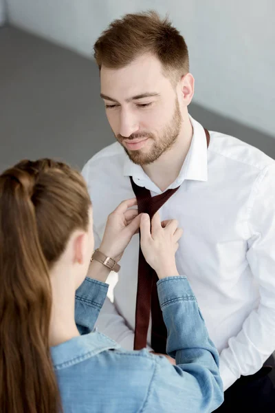 Junge Frau trägt Krawatte auf glücklichen Geschäftsmann zu Hause — Stockfoto