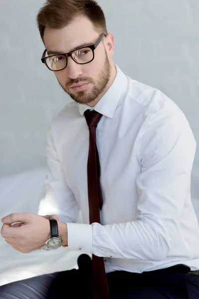 Bel homme d'affaires dans la montre posant près du mur blanc — Photo de stock