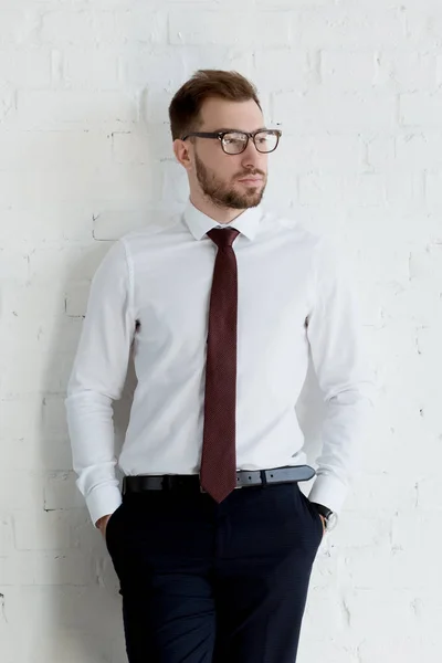 Homem de negócios elegante em óculos posando perto da parede branca — Fotografia de Stock