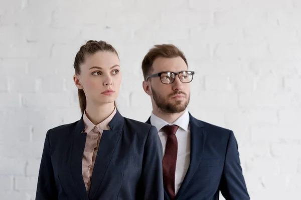 Selbstbewusste Geschäftsleute in formeller Kleidung posieren nahe der weißen Wand — Stockfoto
