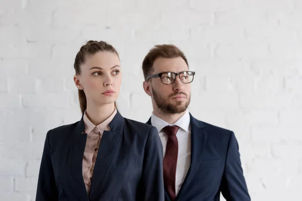 Empresarios seguros en ropa formal posando cerca de la pared blanca - foto de stock