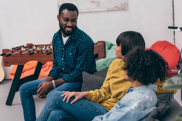 Gruppe multikulturell lächelnder Freunde, die auf der Couch sitzen und miteinander reden — Stockfoto