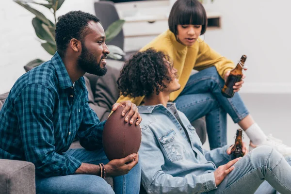 Group of multicultural friends with beer bottles watching american football match — Stock Photo