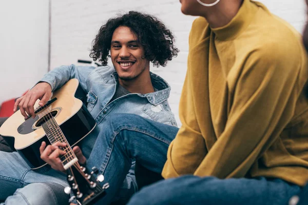 Sorrindo mestiço homem de raça tocando na guitarra acústica para namorada — Fotografia de Stock