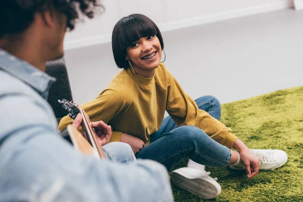 Cropped image of man playing on guitar to mixed race girlfriend — Stock Photo