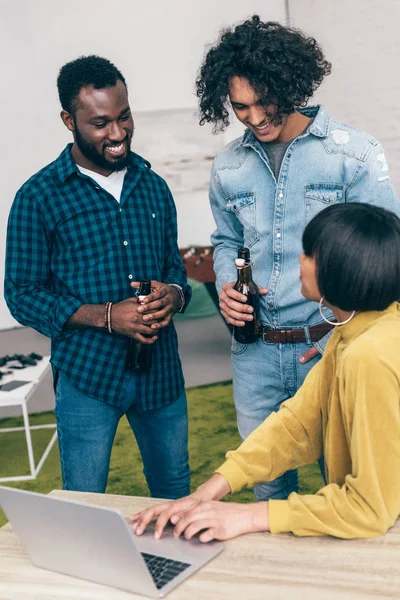 Young woman showing laptop screen to multiethnic male friends — Stock Photo