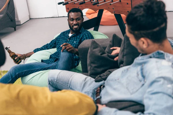 Imagen recortada de grupo de amigos multiétnicos sentados y hablando entre sí - foto de stock