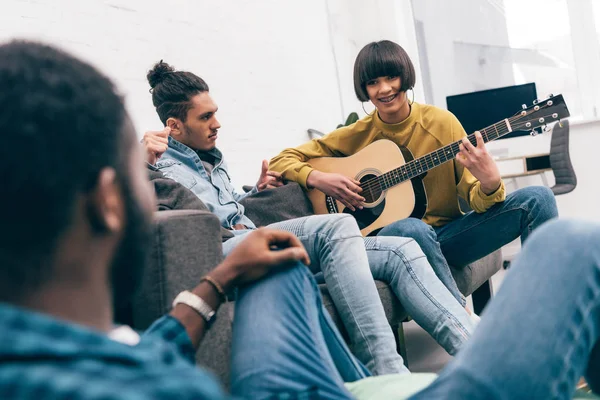 Razza mista giovane donna che suona la chitarra agli amici — Foto stock