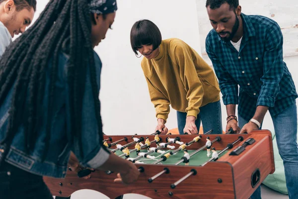 Young multiethnic friends playing table soccer — Stock Photo