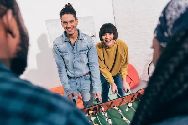 Sonrientes amigos multiétnicos jugando futbolín - foto de stock