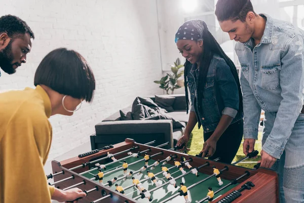 Grupo de jóvenes amigos multiétnicos jugando al futbolín - foto de stock